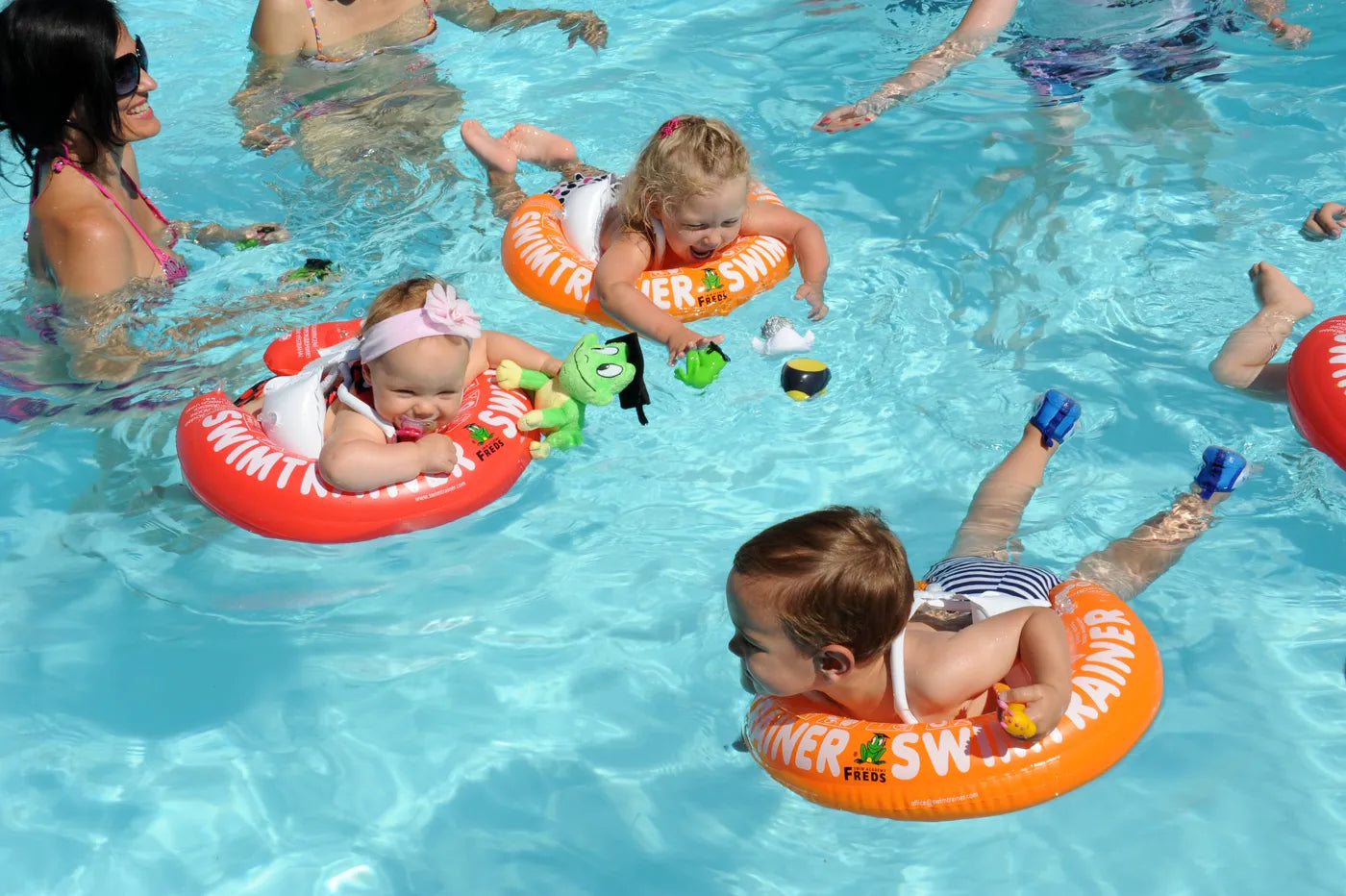 Children using red, orange and yellow SWIMTRAINER swim aids in the pool