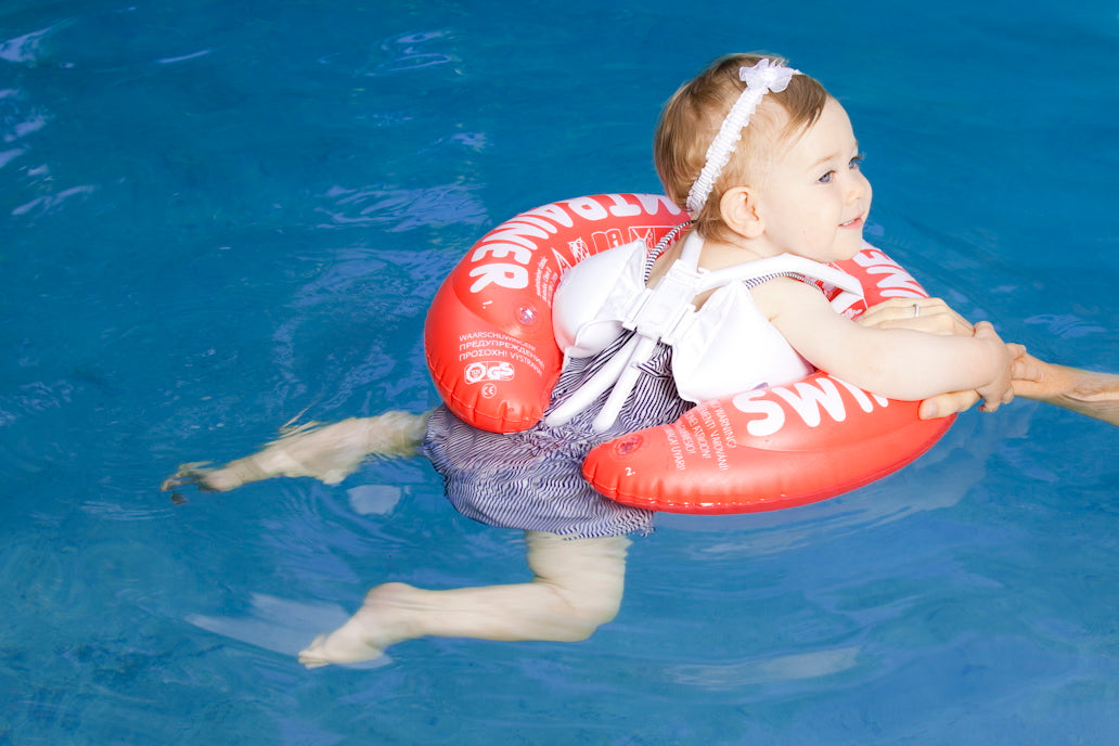 Child practicing with SWIMTRAINER Red and a swim board in the pool